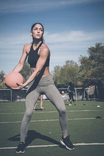 Toned Woman Tossing Medince Ball with a personal trainer in Rochester NY